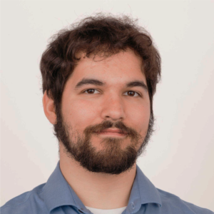 White man with dark brown hair and close-trimmed beard smiles confidently into the camera.