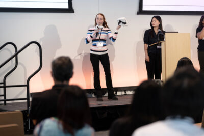 Jazmin Collins holds VR headset on stage, standing next to Crescentia Jung