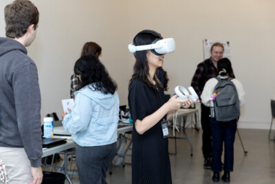 A woman in a dark dress smiles while trying a VR experience