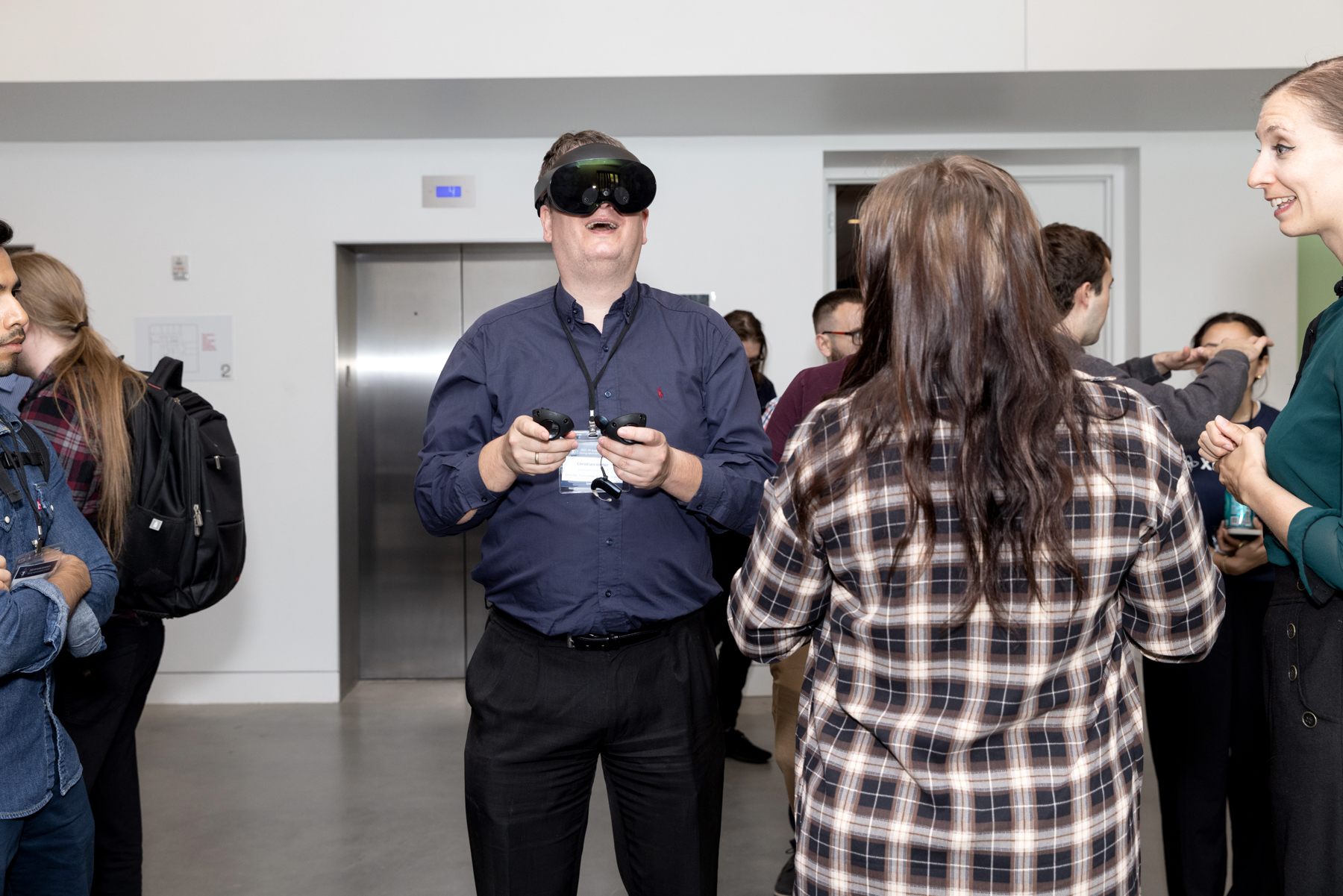 Man wears a VR headset and holds controllers, smiling widely