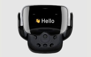 Cognixion One head-mounted display. It has a dark visor with a waving emoji and "Hello" on the front, and brain-computer interface nodes on the back.