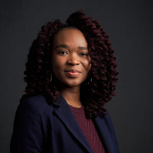 Adelaide Nyanyo, a black woman wearing a maroon blouse and navy blue jacket. 