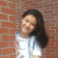 Headshot of Huiran Yu, a young Asian woman peeking out from behind a brick wall.