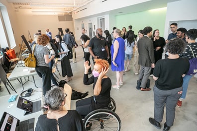 The exhibit hall is crowded with people and tables set with demonstrations of XR accessibility in action.