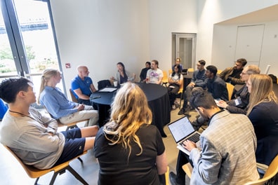Around 15 people form another circle of chairs for the Neurodiversity and XR breakout discussion in the lobby.