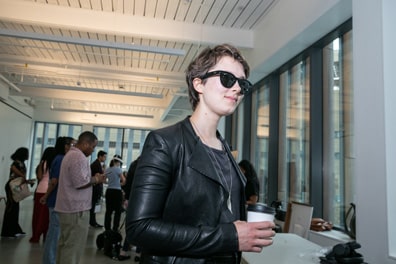 A participant walks across the exhibition hall floor, looking cool in a leather jacket, Meta Rayban shades, and a confident smile.