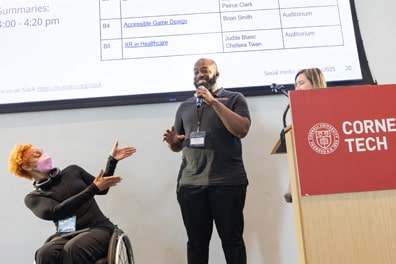 Alice Sheppard, a multiracial Black woman with coffee-colored skin and platinum blond short curly hair sitting in a wheelchair, gestures emphatically at Steven McCoy, a black man with a bushy black beard, as he talks about their Disability, Content Creation, and the Arts breakout.