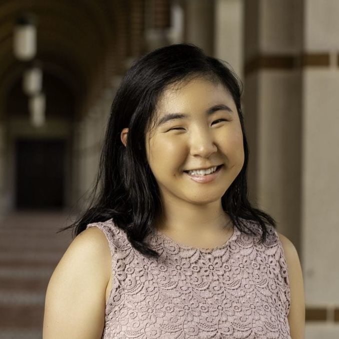 Headshot of Momona Yamagami, a smiling East Asian woman with black hair standing in front of some pillars.