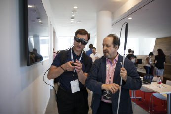 Bill Curtis-Davidson walks with a low-vision user trying out the Magic Leap at the 2019 Symposium